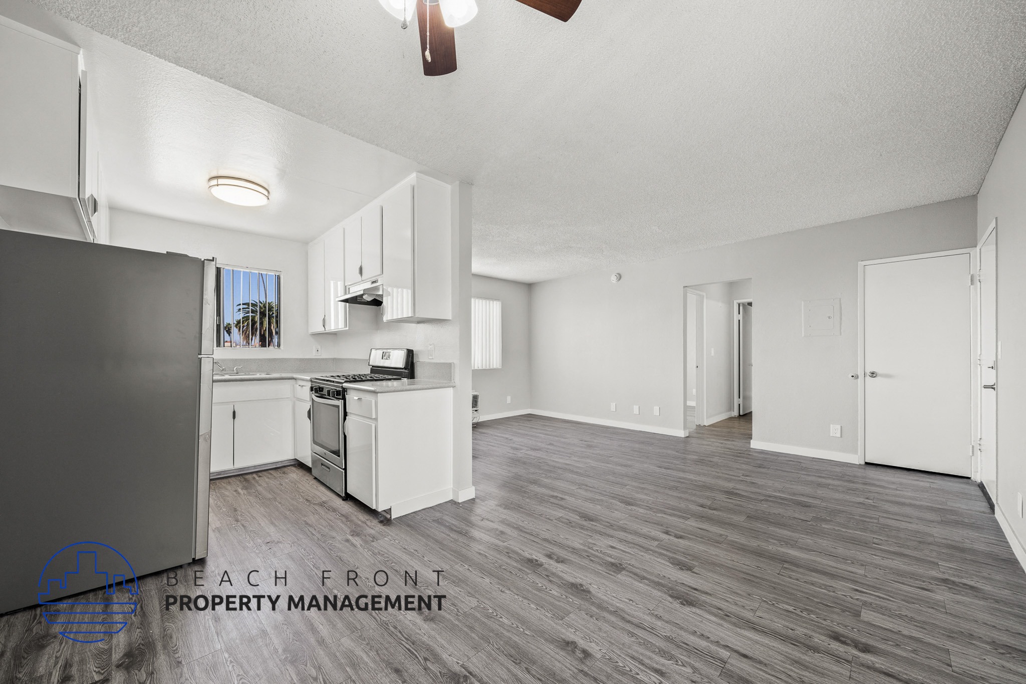 A spacious kitchen with white cabinets and a wooden floor.